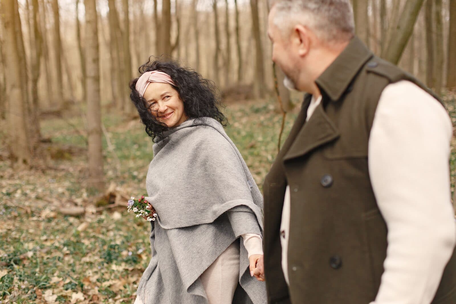 A woman in her fifties laughing with her partner on an autumn walk through the woods