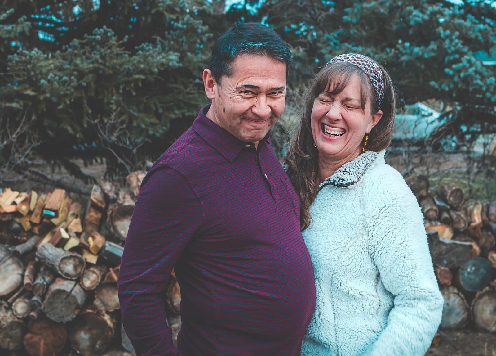 A couple in their fifties laughing together, his arm around her