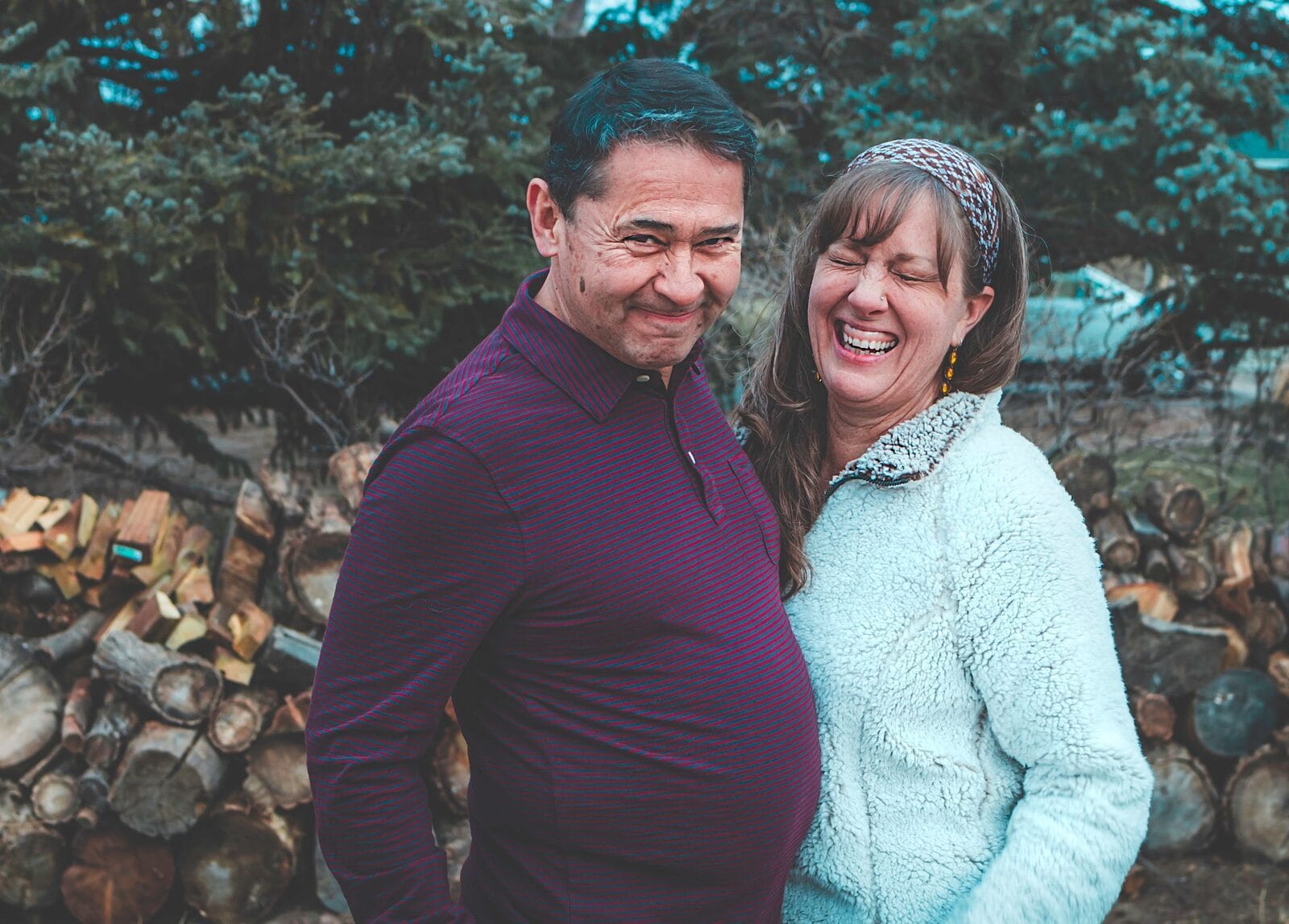 A couple in their fifties laughing together, his arm around her