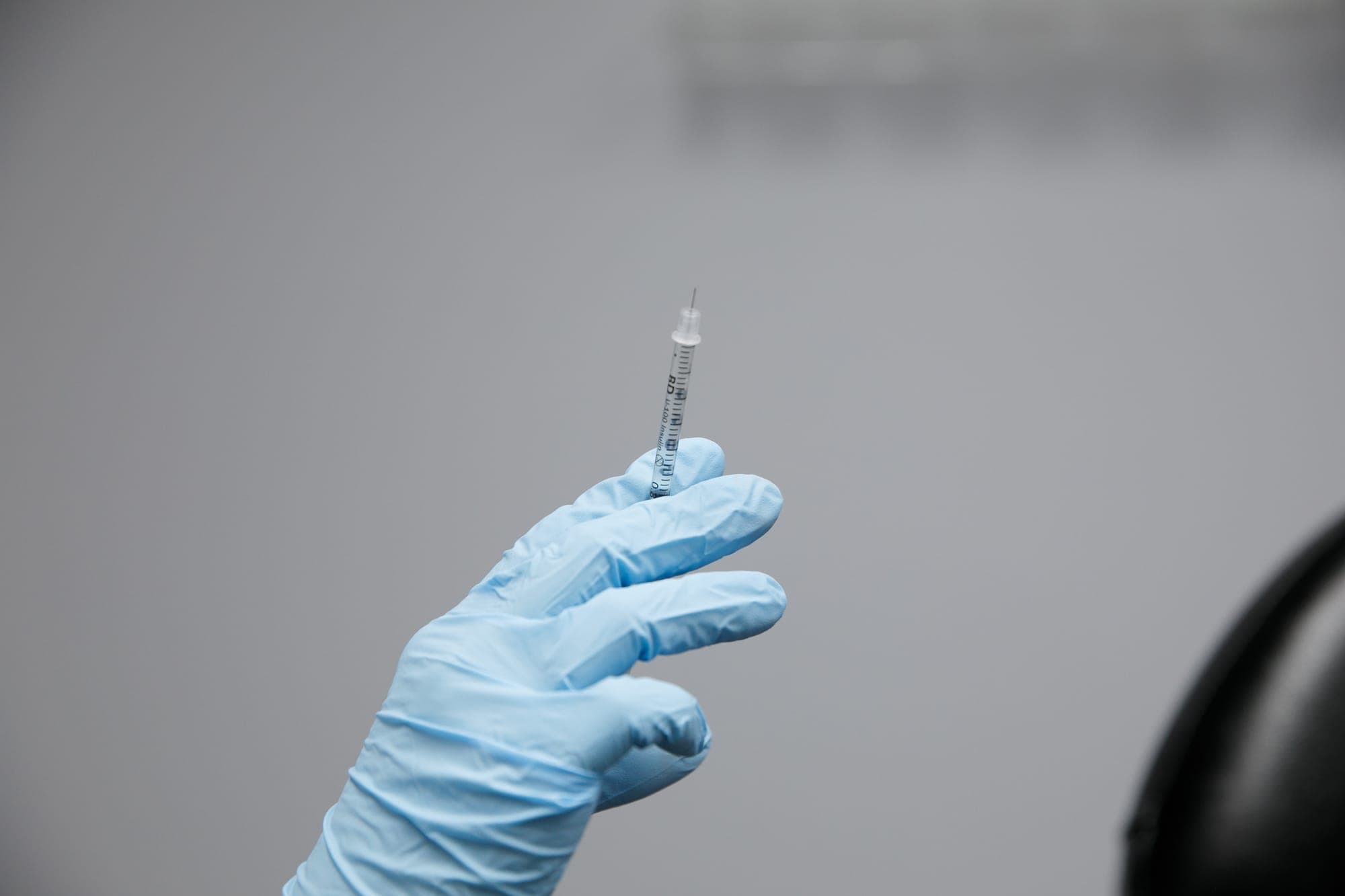 A gloved hand holding a prepared syringe before an injection at La Belle Vie